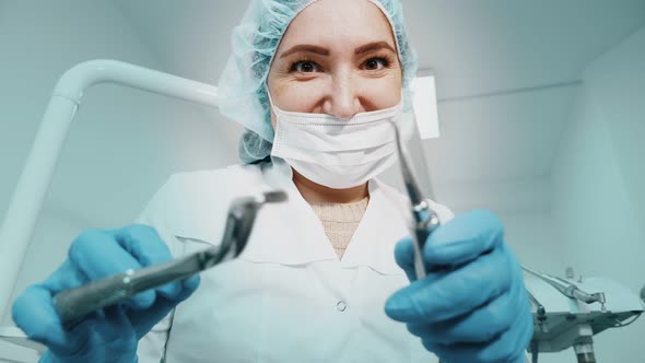 Dentist Woman Doctor Is Holding Dental Instruments Forceps and Needle in Hands and Looking at Camera alt