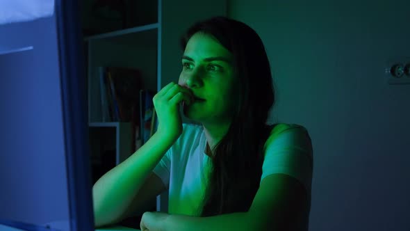 A Woman Watches TV and Bites Her Nails is Nervous and Worried alt