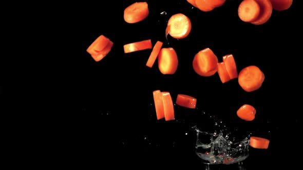 Super Slow Motion Pieces of Carrot Fall Into the Water with Splashes alt