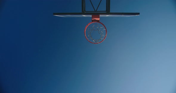 Basketball Players Throw Ball Into Basket Against Blue Sky alt