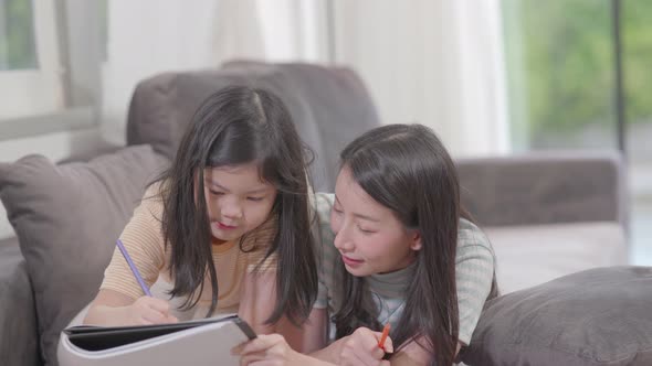 Cute little girl painting a picture and do homework with mother at home