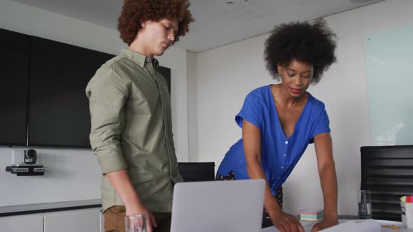 Diverse male and female business colleagues in discussion at work looking at technical drawing alt