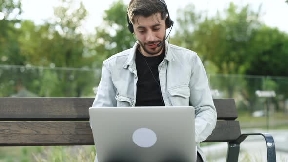 Business Man Wearing Headphones Communicating By Video Call Looking at Laptop Computer