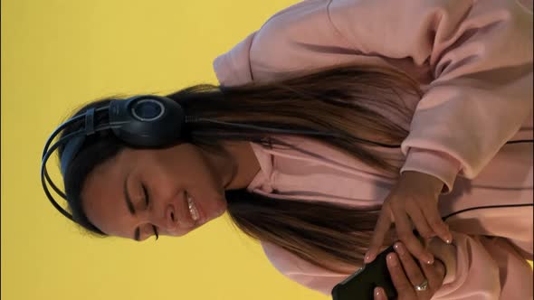 Happy Multiethnic Woman Listening To the Music in Headphones on Yellow Background alt