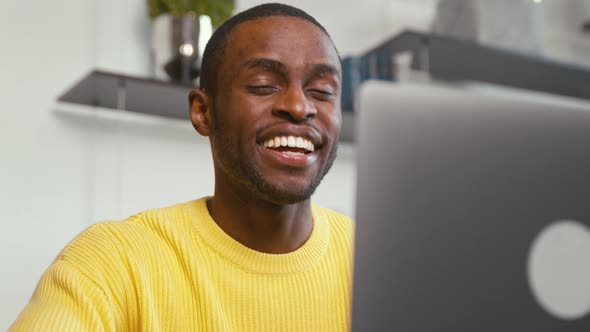 Smiling man calling with webcam at the desk at home office alt
