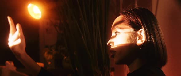 Young woman dances around the a bright spot of light side view alt