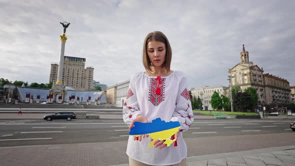 Woman Holds Cut Paper Map of Ukraine Painted in Flag Colors alt