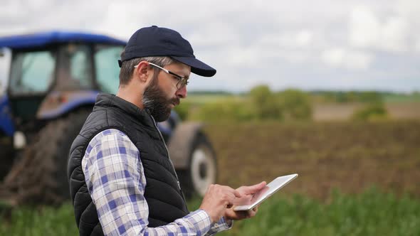 Farmer Uses a Specialized App on a Digital Tablet in Field