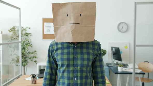 Portrait of Businessman Wearing Paper Bag with No Emotions Emoji Standing in Office alt