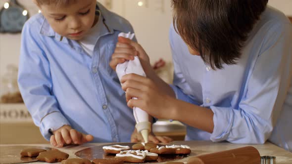 Two Brothers is Decorating a Christmas Cookies with Pastry Bag at Home Kitchen