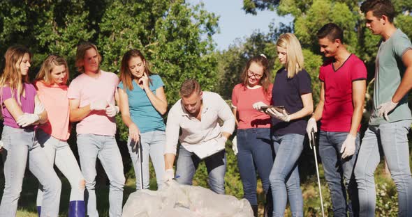 Mid adults volunteering and man taking notes during river clean-up day alt