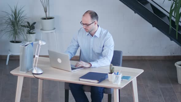 Handsome Businessman Working with Laptop in Office alt