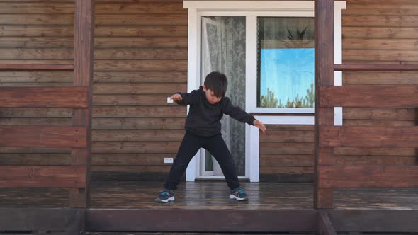 A Child Does Morning Exercises Standing on the Veranda A Small Boy Does Sports on the Terrace