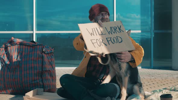 A Beggar is Sitting on the Ground with His Dog alt