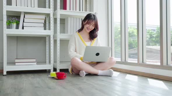 Asian woman working on the floor with laptop in the living room of the house
