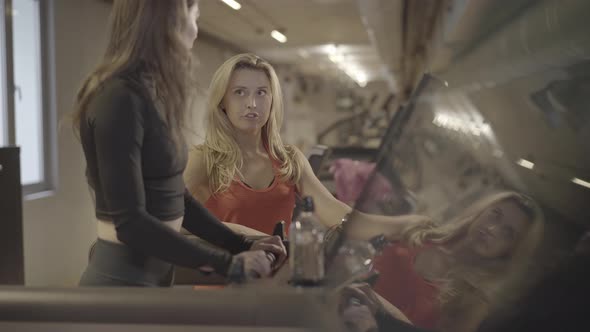 Joyful Blond Brown-eyed Coach Giving High Five To Young Slim Caucasian Woman Walking on Treadmill alt
