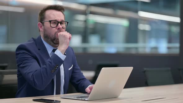 Middle Aged Businessman with Laptop Coughing alt