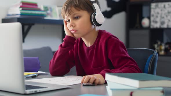 Handheld video of bored boy while studying at home. Shot with RED helium camera in 8K. alt