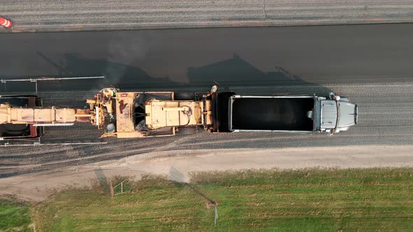 Birds eye view of dump truck refilling aggregate for replacement of highway blacktop.