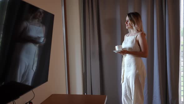 Side View Young Happy Confident Woman with Coffee Cup Looking Out the Window Smiling alt