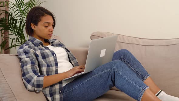 Beautiful Female Freelancer Working at Home Online Lying Down with a Laptop