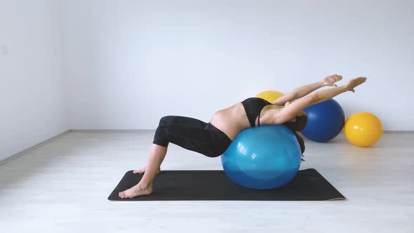 Slow motion shot of pregnant woman laying on exercise ball