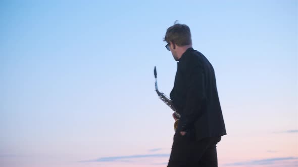 Real Jazz Bearded Singer in Black Jacket and Sunglasses with Saxophone Enters Frame at Sunset or alt