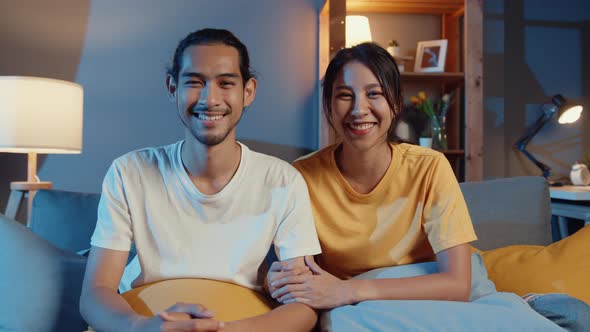 young asia couple man and woman looking at camera smile and cheerful on video call online at night .