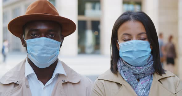 Medium Shot of Loving African Couple Wearing Protective Mask Looking at Camera Outdoors alt