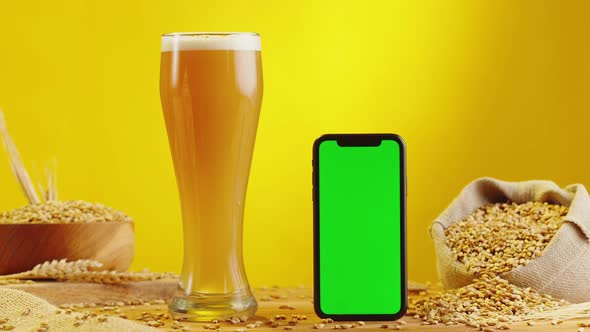 Foamy Beer in Glass and Phone with Green Chroma Key Screen alt