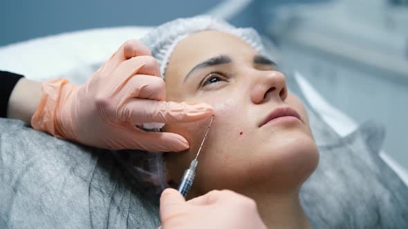 Doctor Cosmetologist Makes Several Biorevitalization Injections Into the Skin of a Woman's Face alt