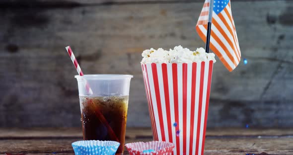 Popcorn, confectionery and drink on wooden table alt