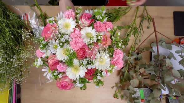 Top view of the hands of a young female florist creating a composition alt