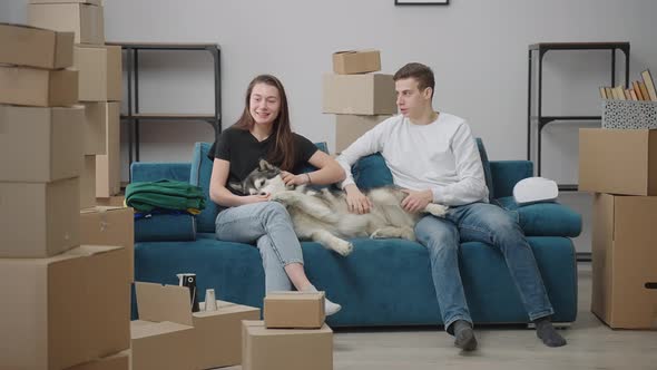 Young Man and Woman are Sitting on the Couch in a New Apartment alt