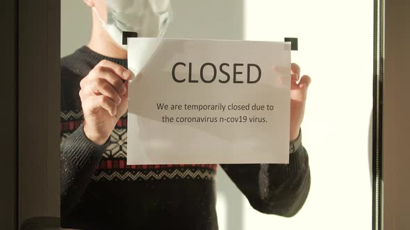 Owner of the Institution Hangs a Closed Sign on the Window alt