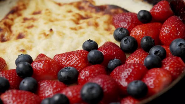 Fried Curd Pie in a Frying Pan with Strawberries and Blueberries on a Wooden Table alt
