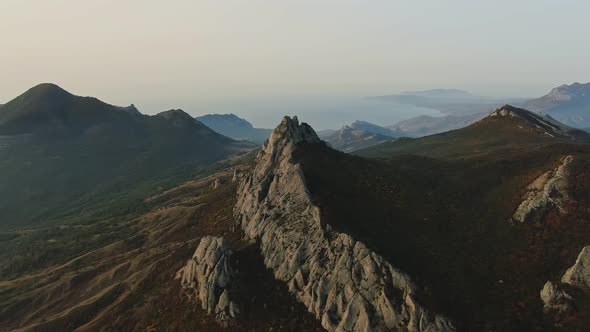 Aerial Slow Motion Footage of a Rocky Mountain Range Covered with Autumn Forest and a Sea Bay on the alt