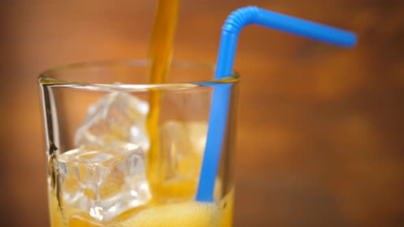 Orange Soda Pouring Into Glass with Ice Cube alt