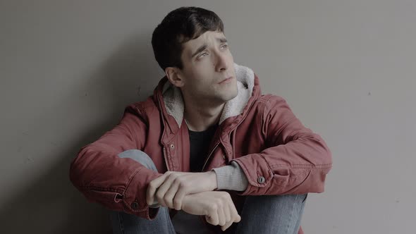 depressed lonely young man sitting on ground looking alt