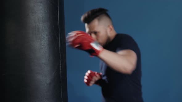 Muscular Handsome Fighter Giving a Forceful Forward Kick During a Practise Round with a Boxing Bag alt