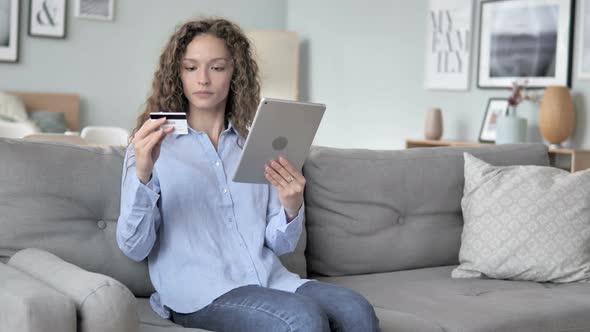 Online Shopping on Tablet by Curly Hair Woman Sitting on Couch alt