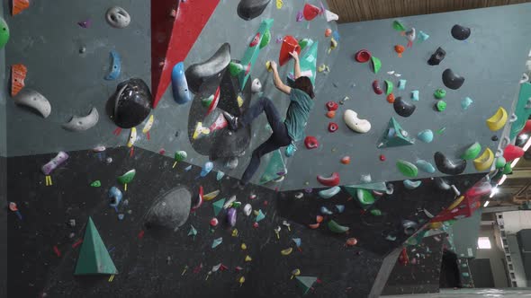 Man Climbs the Wall Training on a Climbing Wall Practicing Rockclimbing Mountaineer Training alt
