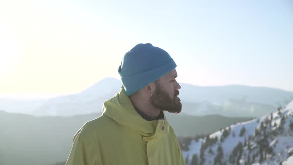 Slow Panning Shot of Confident Bearded Man Overlooking Mountains at Sunrise