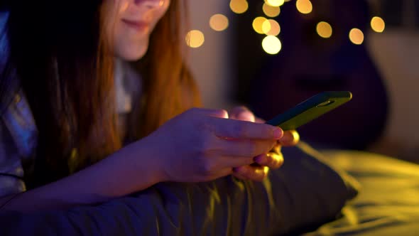 Asian woman using smart phone on the bed at night.