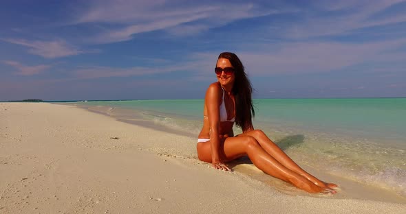 Beautiful happy lady on photoshoot having fun at the beach on summer white sand and blue 4K backgrou alt