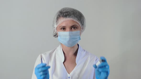 Caucasian Female Doctor or Nurse Holds a Syringe and a Vaccine Bottle