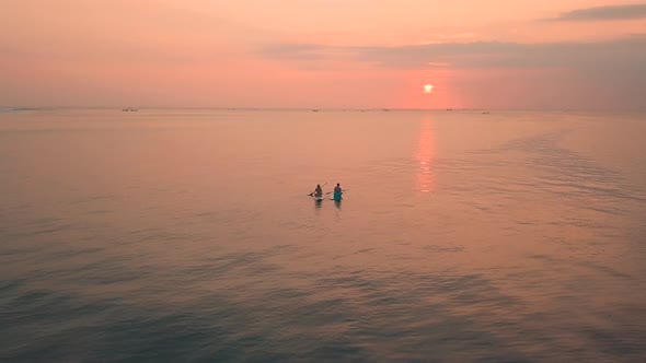 Two Young Women Enjoying an Incredible Orange Sunset in the Ocean. 