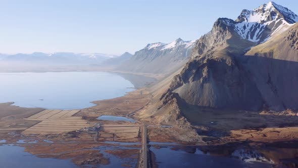 Aerial Over an Empty Dirt Road Along Fjord and Mountains alt