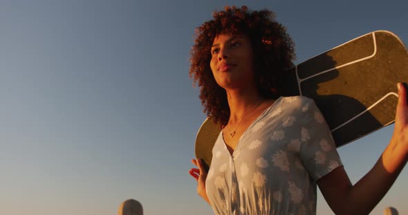 Woman walking and holding a skateboard on hand alt