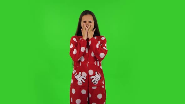 Beautiful Girl in Red Fleece Pajamas Is Yawning, Bedtime Concept. Green Screen alt